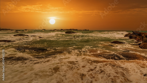 beautiful sunset over the ocean with rocks in the foreground