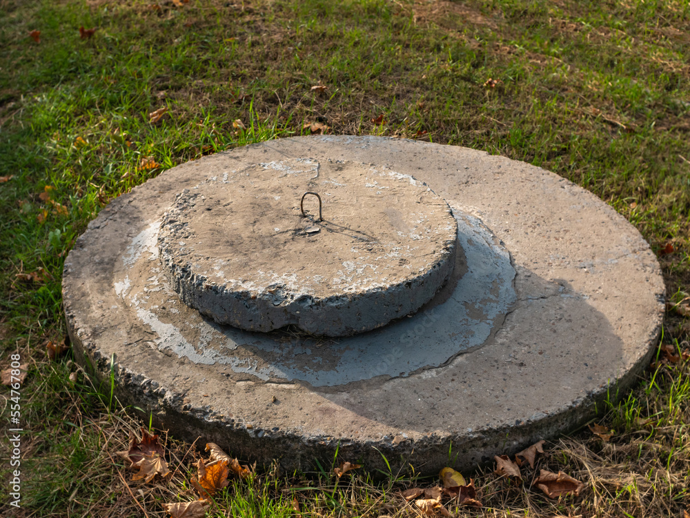 Round concrete manhole on a concrete base. City sewerage system. A concrete manhole covers the entrance to the city's sewer system.