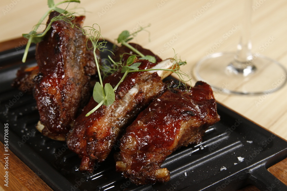 Roasted pork ribs on a rectangular metal hot plate