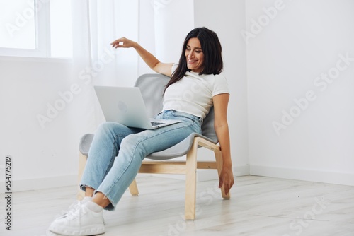 Woman relaxing at home sitting in a chair with a laptop, lifestyle home mood. Mockup, free copy space