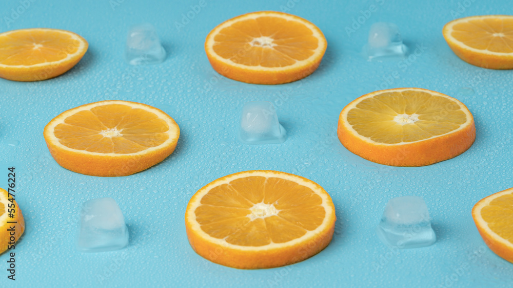 Fototapeta premium Juicy oranges on a background of ice cubes with copy space on a blue background