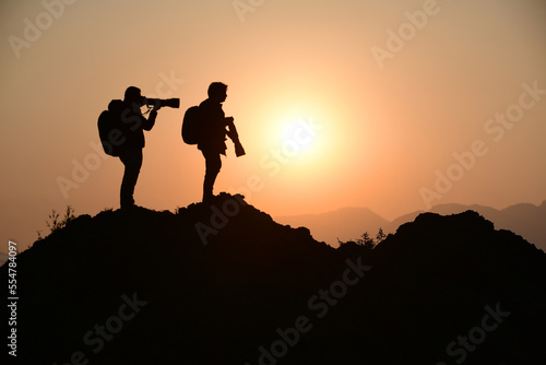 Artistic silhouette, Two wildlife photographer taking pictures during sunset from a peak 