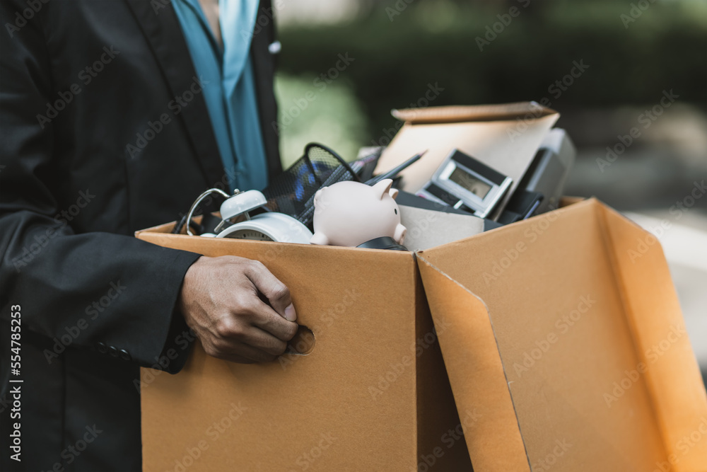 Businessman fired or resign from the company are carrying boxes down the street looking for a new job. Unemployed, hiring job, quitting job concept..