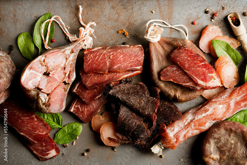 Fotografie Various smoked and cured meat snacks over concrete table background