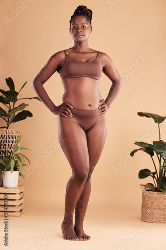 Obraz na plátne Portrait, body and beauty with a model black woman in studio on a beige background with hands on hips