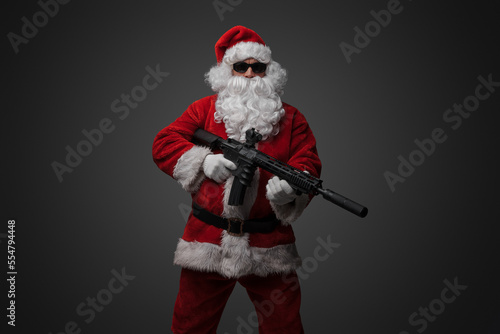 Shot of santa claus gunslinger with rifle and sunglasses dressed in red costume.