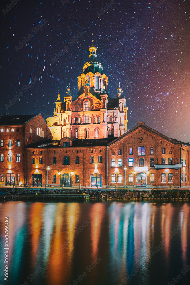 Helsinki, Finland. Bright Starry Rotation Sky. View Of Kanavaranta Street With Uspenski Cathedral In Evening Night Illuminations. Stars Movement Lines.