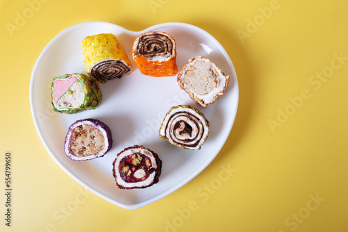 Traditional Turkish dessert Turkish delight on a plate in the form of a heart on a yellow background.
