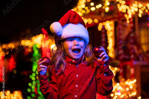 Kids winter holidays and celebration. Child at christmas house outdoor. Christmas decoration in front of a house.