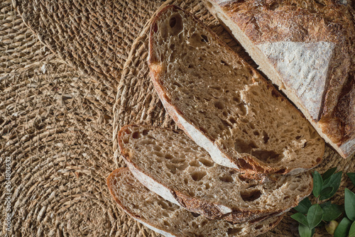 Pieces of fresh homemade sourdough bread. Slicing artisan bread on a straw lining, top view.