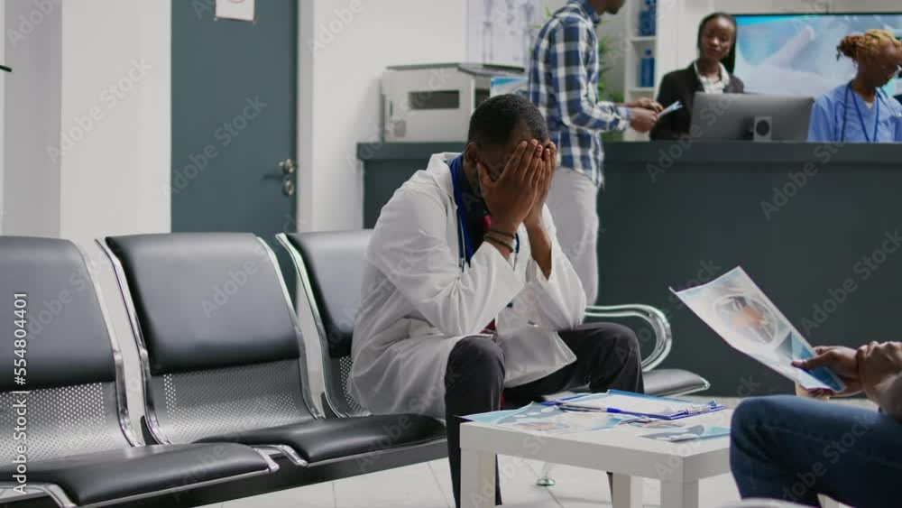 Tired frustrated physician sitting in hospital lobby, feeling overworked and stressed at facility reception waiting room. Exhausted doctor thinking about disease treatment in waiting area. Tired frustrated physician sitting in hospital lobby, feeling overworked and stressed at facility reception waiting room. Exhausted doctor thinking about disease treatment in waiting area.