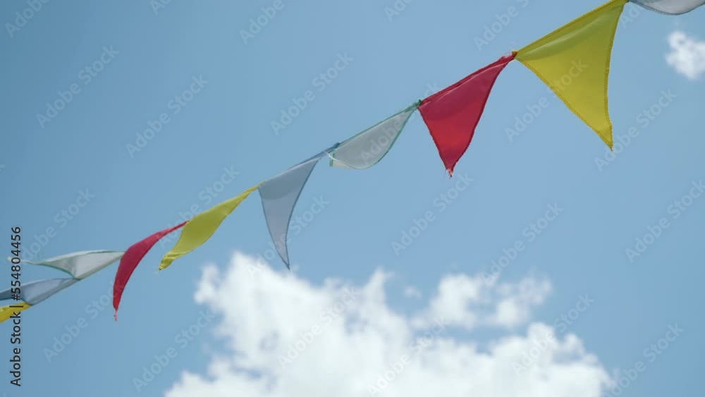 Close-up shot festive red and yellow triangular flags on cord moving in wind against blue sky. Colorful flags under blue sky in windy day at slow motion Close-up shot festive red and yellow triangular flags on cord moving in wind against blue sky. Colorful flags under blue sky in windy day at slow motion