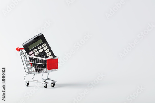 Obraz na plátne Shopping cart trolley and calculator on white background with copy space