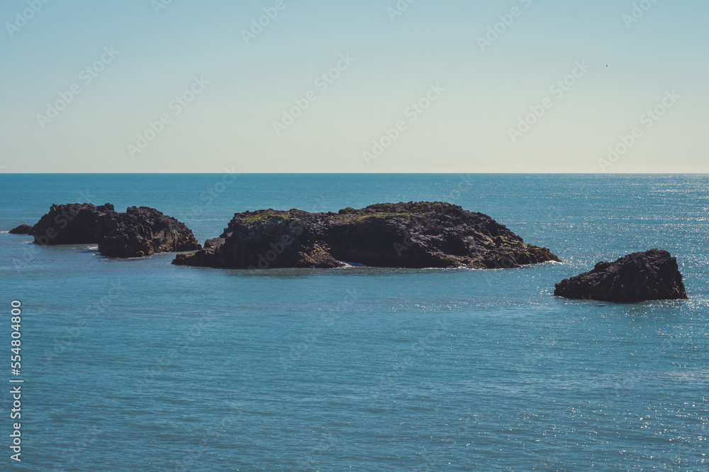 Large rocks in sea water landscape photo. Beautiful nature scenery photography with blue sky on background. Idyllic scene. High quality picture for wallpaper, travel blog, magazine, article
