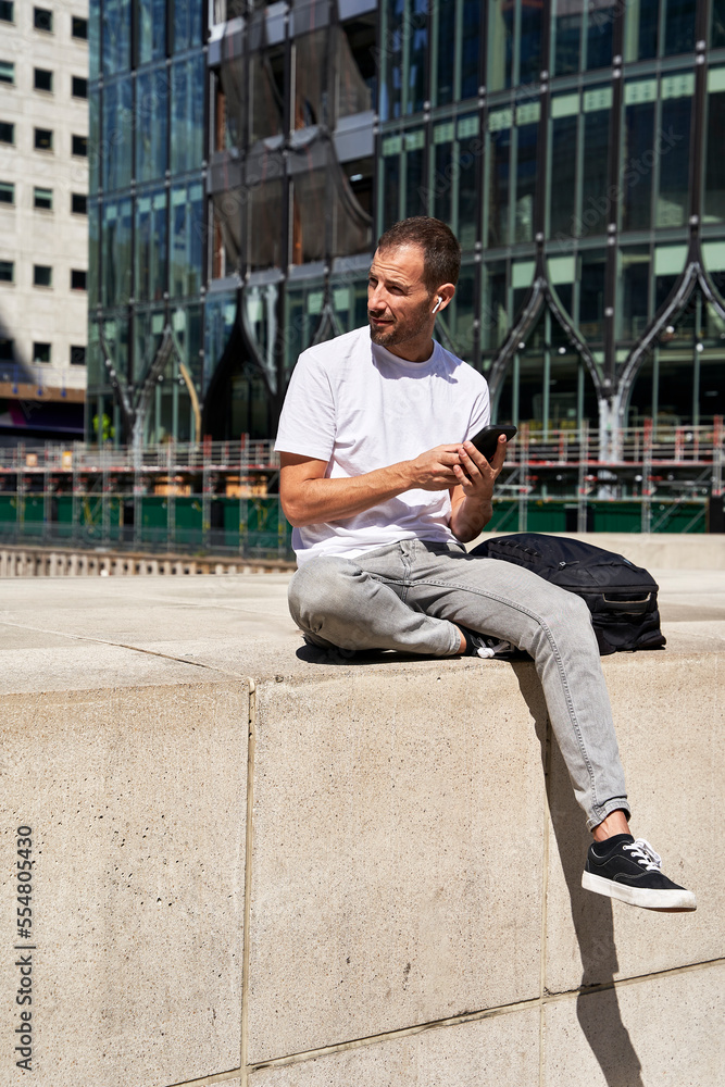 Man with smart phone sitting in front of building Man with smart phone sitting in front of building