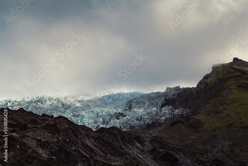 Rocky mountain ridge with ice landscape photo. Beautiful nature scenery photography with gloomy sky on background. Idyllic scene. High quality picture for wallpaper  travel blog  magazine  article