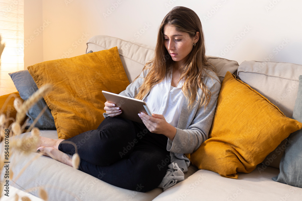 Young woman using tablet PC on sofa at home Young woman using tablet PC on sofa at home