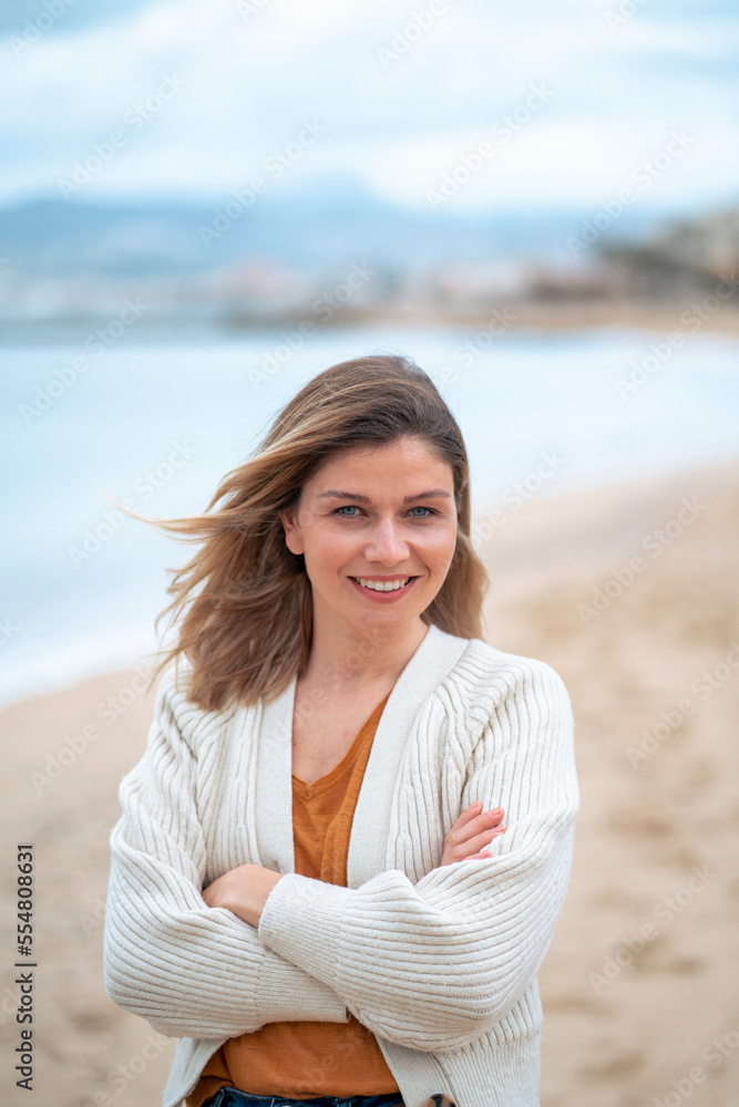 Smiling beautiful young woman with arms crossed standing at beach Smiling beautiful young woman with arms crossed standing at beach