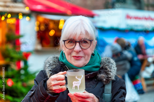 Smiling senior woman with cup of mulled wine at Christmas market photo