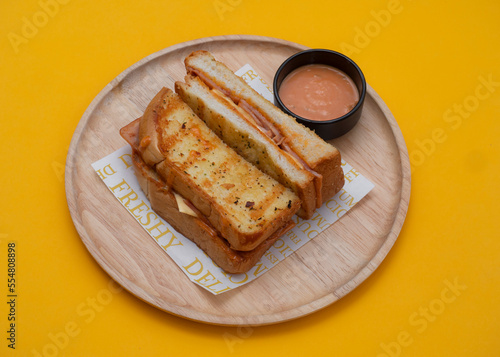 Bacon egg cheese sandwich toast with wooden plate on yellow background.