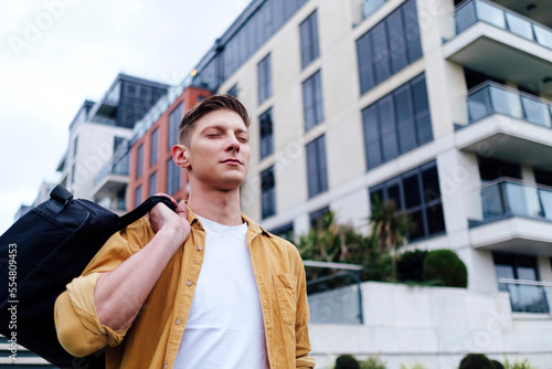 Wallpaper Mural Handsome young man with eyes closed carrying bag Torontodigital.ca