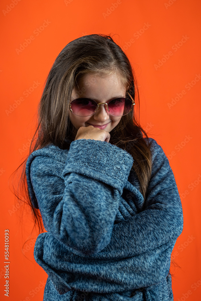 Cheerful cute little girl in a bathrobe isolated on a bright orange background.