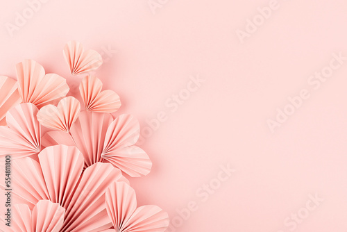 Valentines day background - pink paper ribbed hearts fly on soft light pastel pink background as sideways border with copy space  top view.