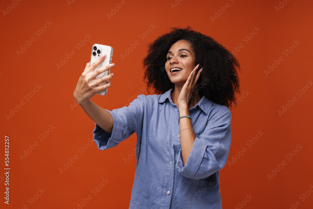 Young woman with curly hair using cellphone for selfie photo Young woman with curly hair using cellphone for selfie photo