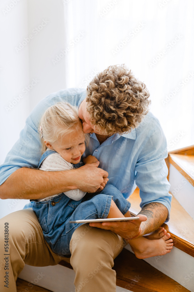 Young father and his daughter using tablet computer on stairs at home Young father and his daughter using tablet computer on stairs at home