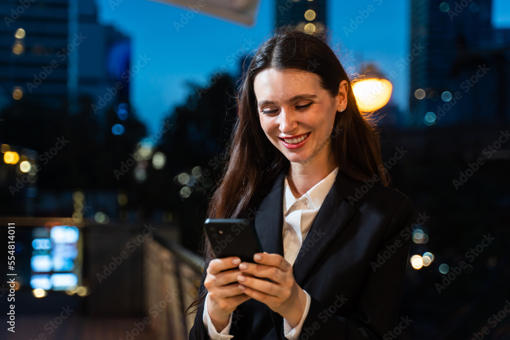 Caucasian businesswoman using mobile phone, working in city at night. Caucasian businesswoman using mobile phone, working in city at night.