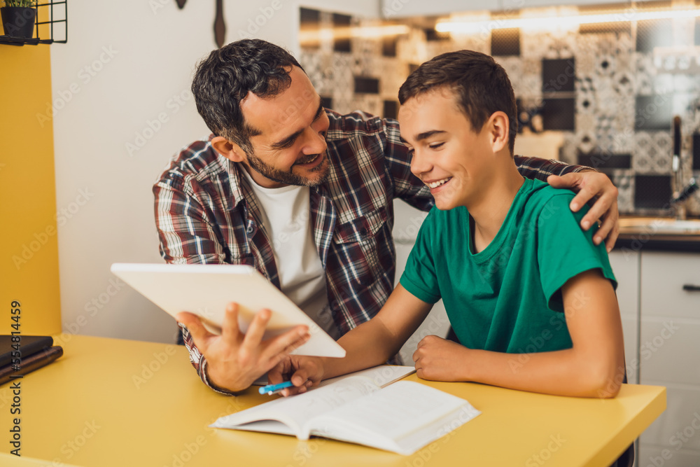 Father is helping his son with learning. They are doing homework together. Father is helping his son with learning. They are doing homework together.