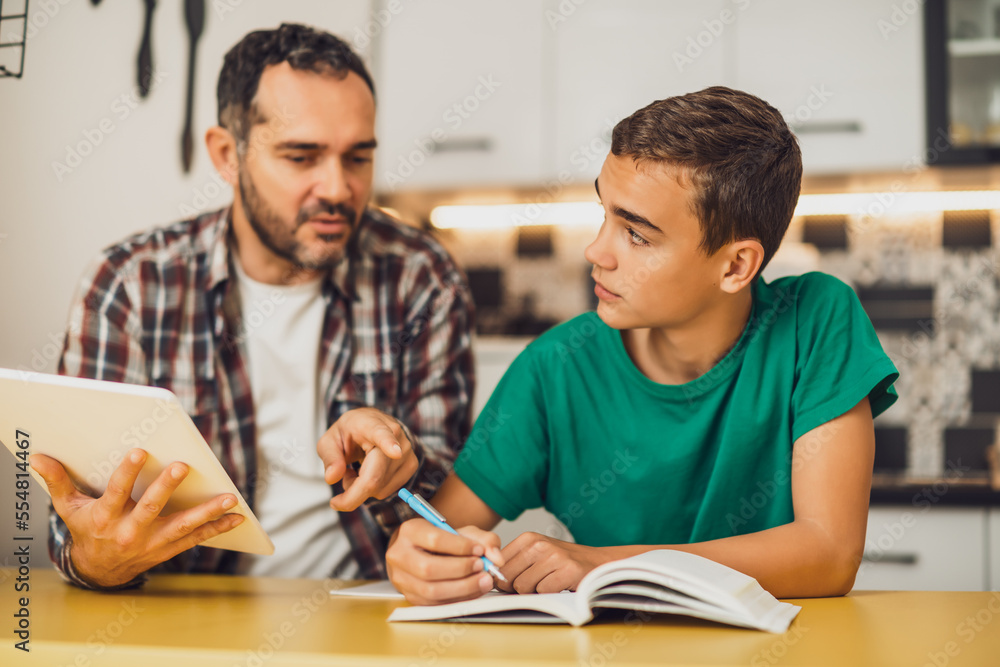 Father is helping his son with learning. They are doing homework together. Father is helping his son with learning. They are doing homework together.