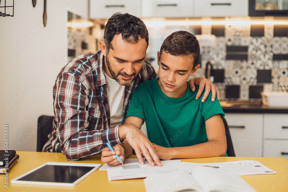 Father is helping his son with learning. They are doing homework together. Father is helping his son with learning. They are doing homework together.