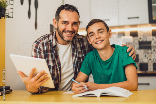 Father is helping his son with learning. They are doing homework together.