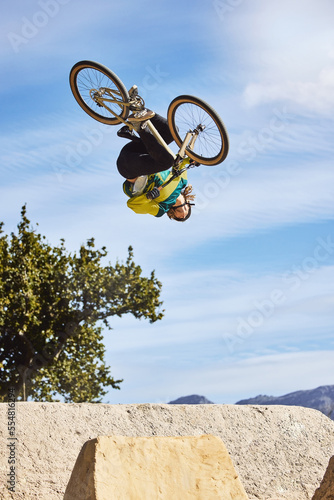 Cycling sports, bike and jump of man performing stunt outdoors in nature. Trick, dangerous risk and biker, rider or bmx athlete on bicycle jumping on ramp for training exercise, workout and fitness