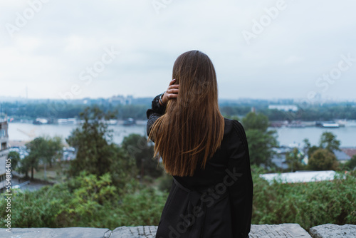 Rearview shot of a young adult woman looking over a river in belgrade city.