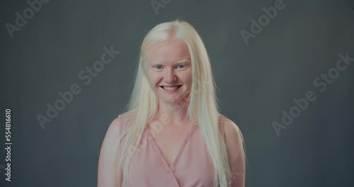 NATURAL BEAUTY Happy young albino woman, college student smiling cheerfully at camera isolated at gray background. photo
