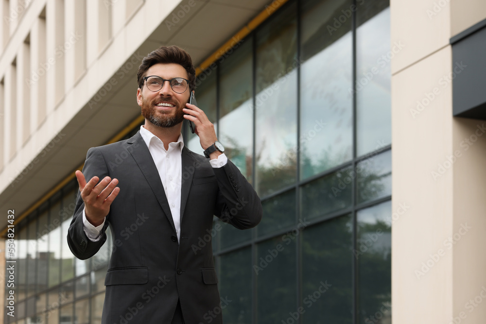 Handsome businessman talking on smartphone while walking outdoors, space for text Handsome businessman talking on smartphone while walking outdoors, space for text
