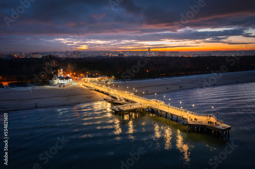 Illuminated pier in Brzezno on the winter beach at dusk, Gdansk.  Poland.