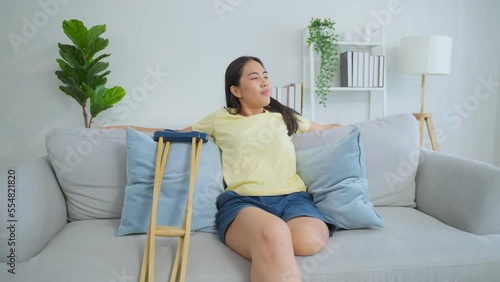 Asian young amputee leg woman lying down on comfort sofa in living room. photo