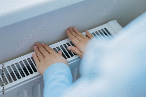 child warming hands over heater. Energy crisis in Europe