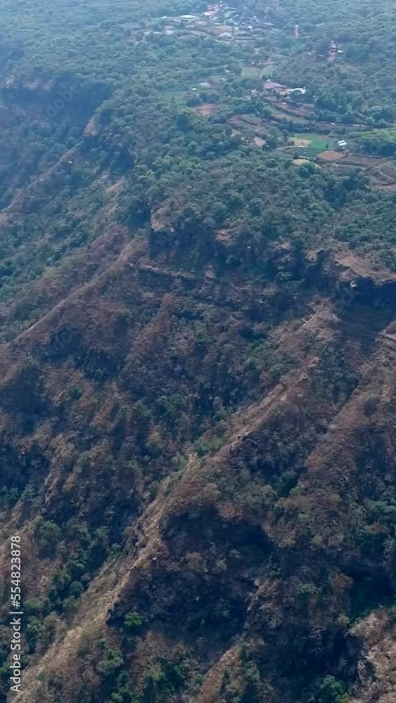 Vertical aerial video of steep hill side covered in tropical vegetation, fields on top Vertical aerial video of steep hill side covered in tropical vegetation, fields on top