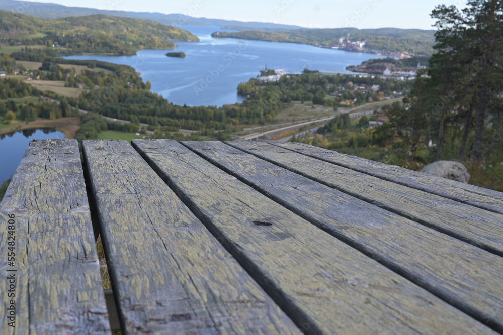 An old wooden table on a mountain, a view of a valley with a lake and a small town.