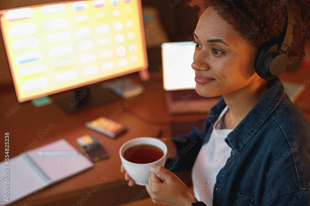 Afro american woman graphic designer drinking tea during break at home office. Freelance concept Afro american woman graphic designer drinking tea during break at home office. Freelance concept