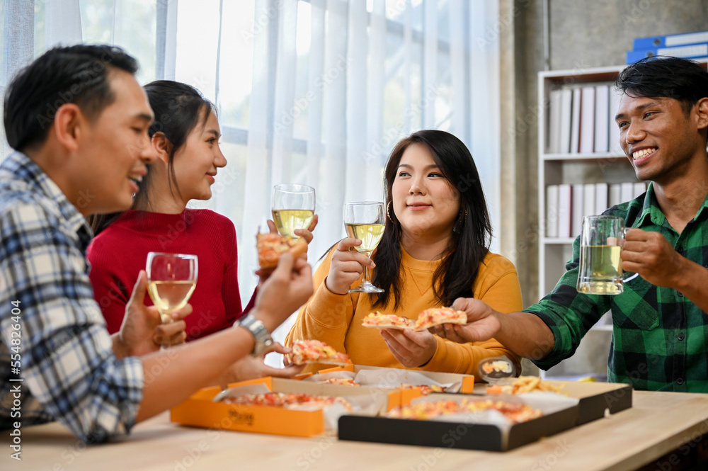 Group of happy and joyful Asian coworkers drinking wine and eating pizza in the office. Group of happy and joyful Asian coworkers drinking wine and eating pizza in the office.
