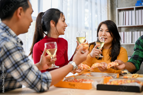 Group of diversity Asian friends enjoy talking  drinking wine and eating pizza in the party.