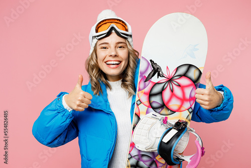 Snowboarder satisfied fun smiling woman wear blue suit goggles mask hat ski padded jacket show thumb up isolated on plain pastel pink background Winter extreme sport hobby weekend trip relax concept