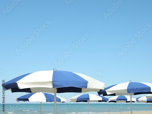 Many blue and white beach umbrellas near sea
