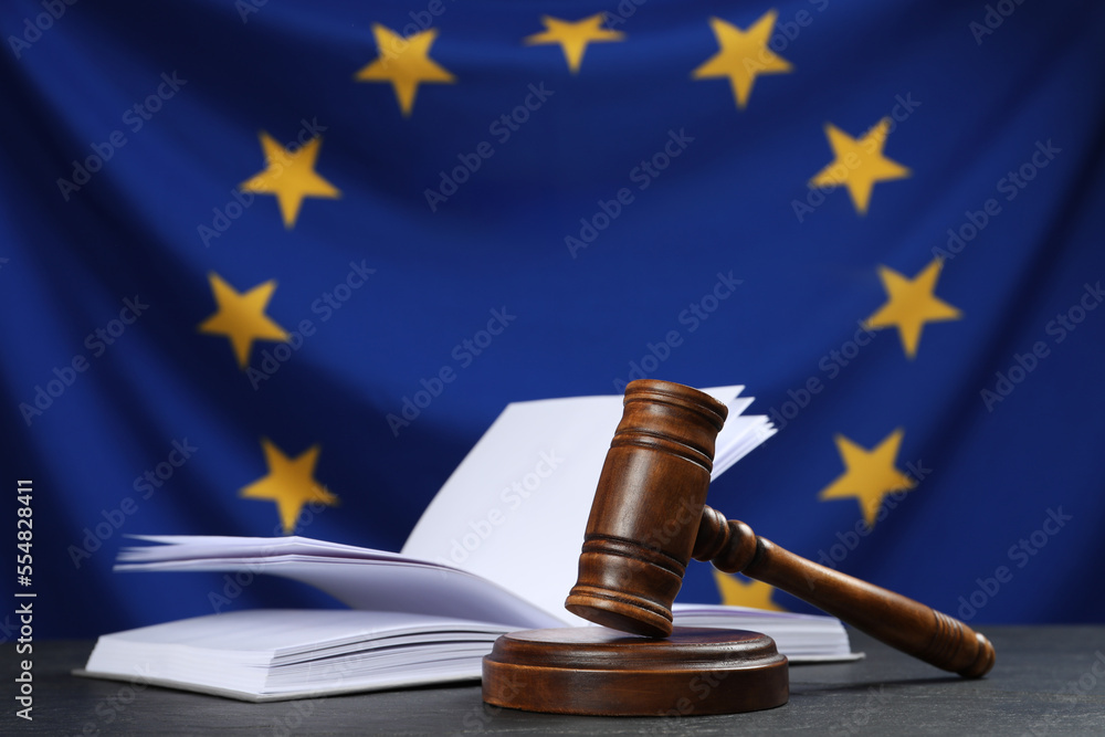 Judge's gavel and open book on black table against flag of European Union