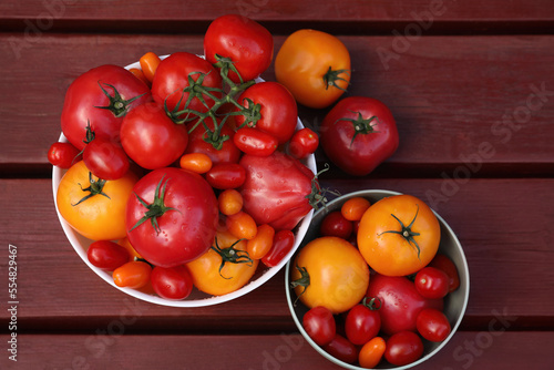Bowls with fresh tomatoes on wooden table, flat lay